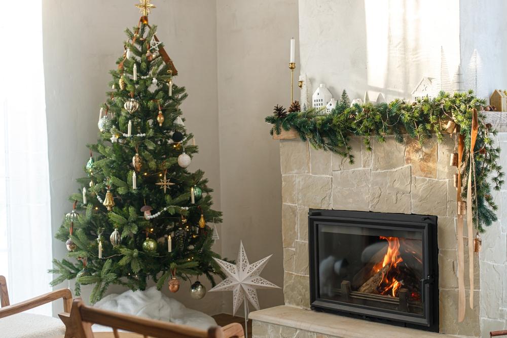 decorated christmas tree with vintage baubles and modern decor on fireplace mantel with bells and ribbon