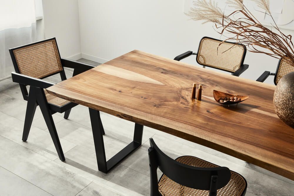 Interior design of stylish dining room interior with family wooden table, modern chairs, plate with nuts, salt and pepper shakers.