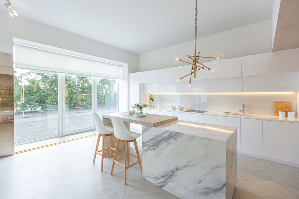 A modern trendy snow white kitchen in minimalistic style with island and two bar stools