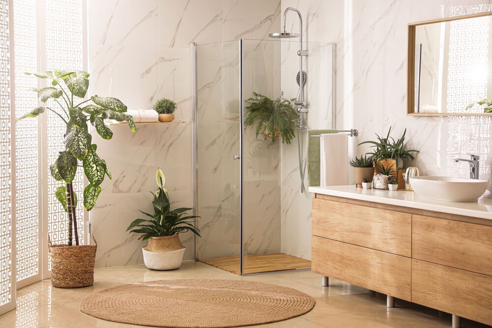 Stylish bathroom interior with countertop, shower stall and houseplants.