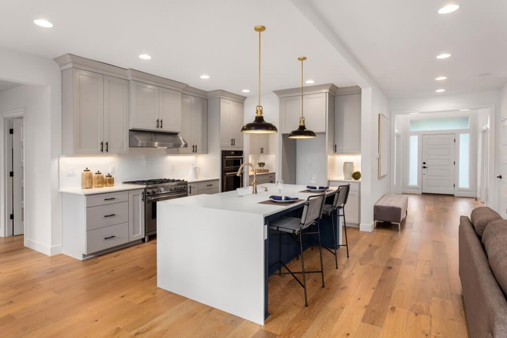 Kitchen with waterfall island, stainless steel appliances, pendant lights, and hardwood floors