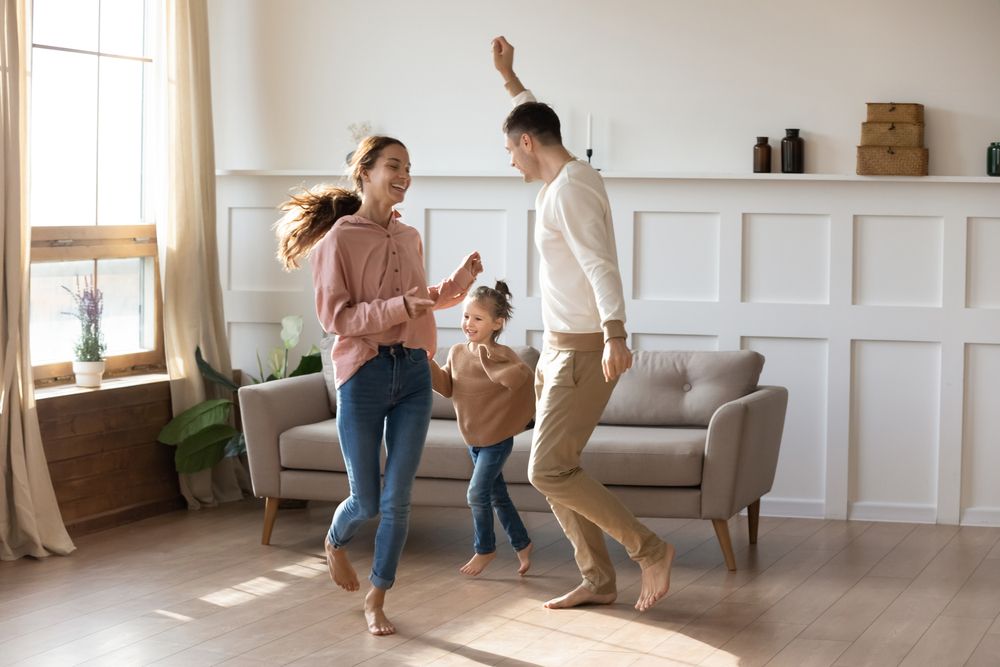 a family of three jumping in a living room